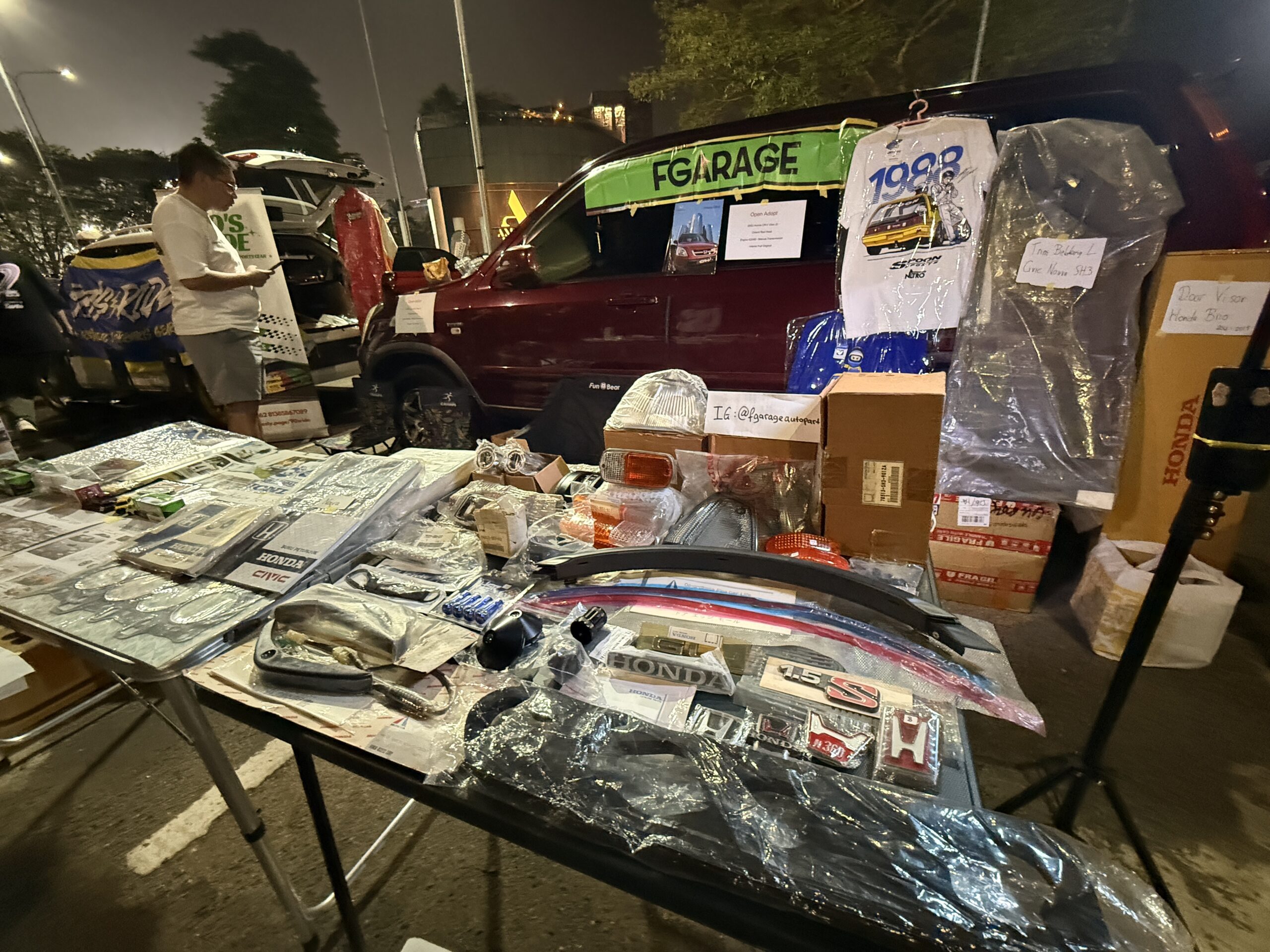 Lapak suku cadang Honda berisi lencana, emblem H, buku manual Civic, dan kaus Spoon Sports