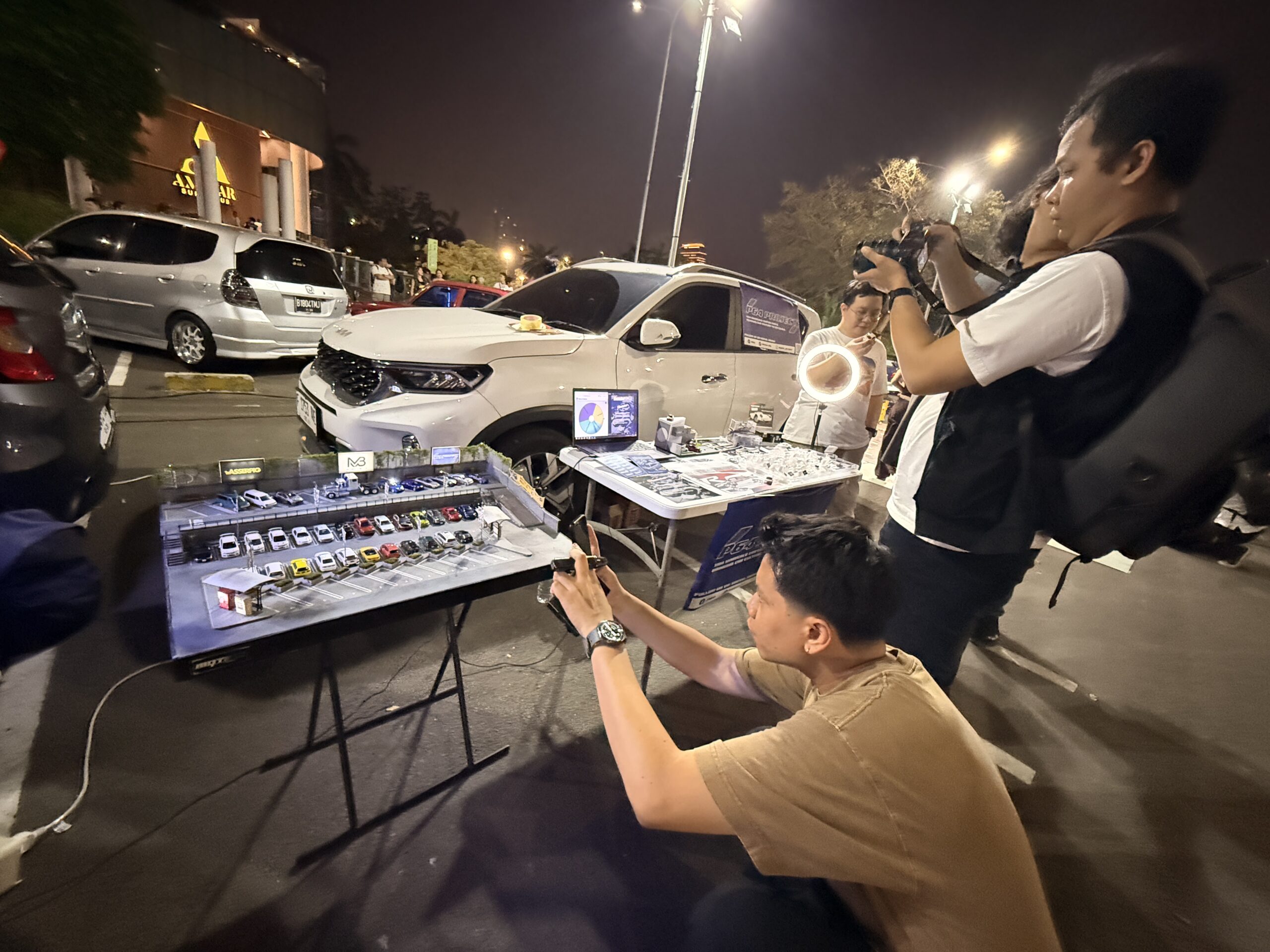 Pengunjung memotret diorama parkir bertingkat berisi mobil miniatur