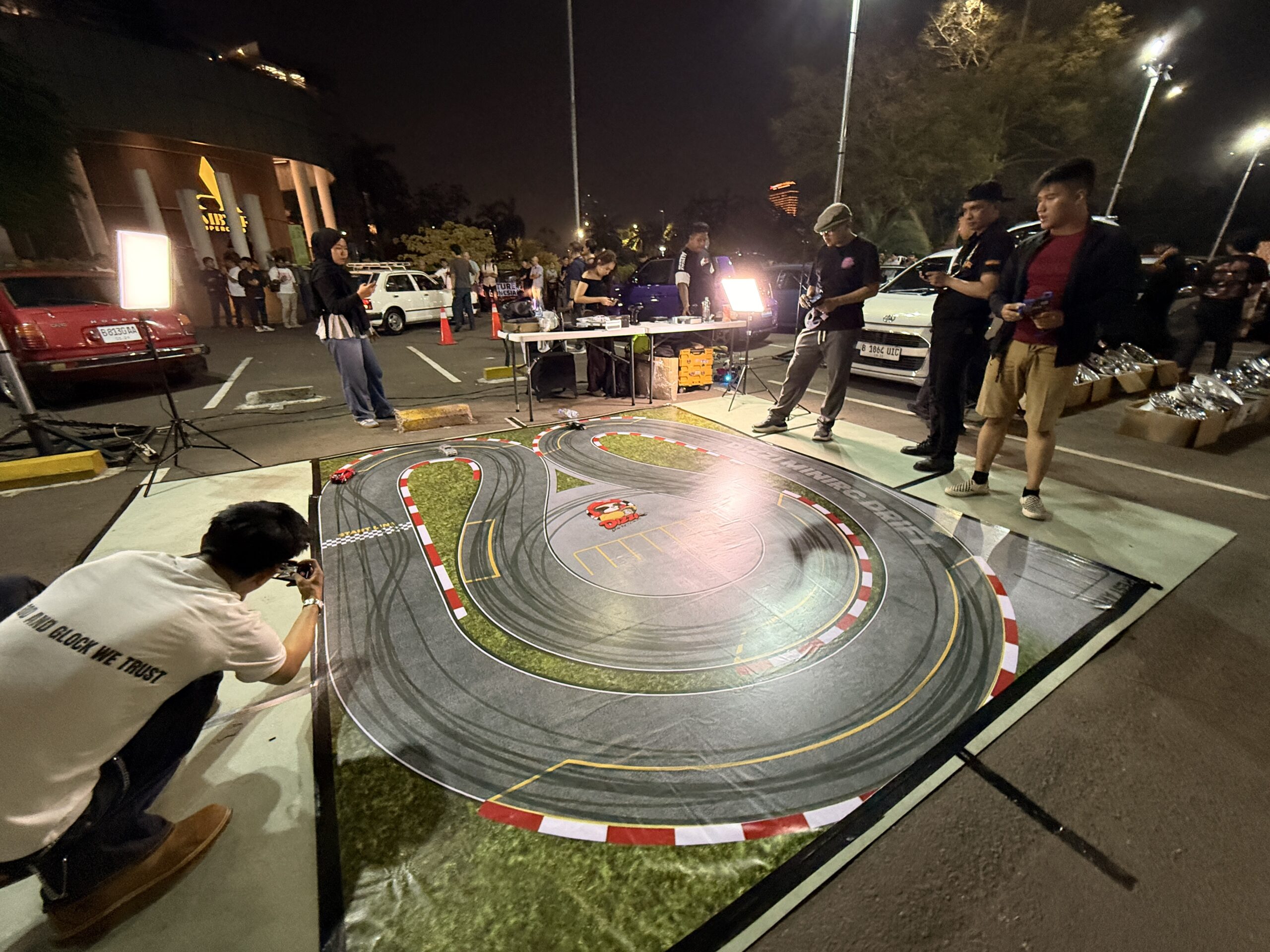 Lintasan RC drift di aspal parkiran dengan bekas ban pada karpetnya